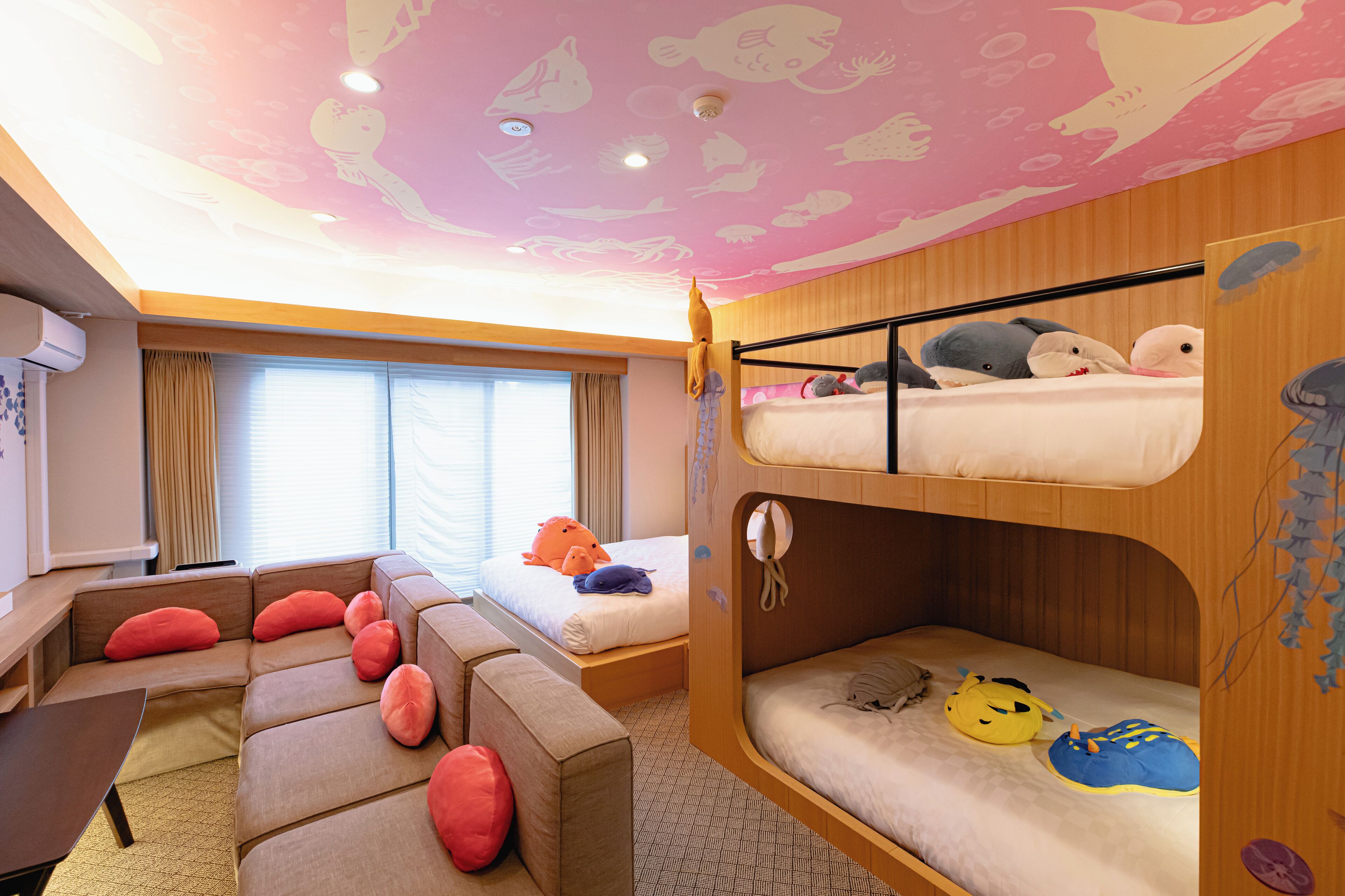 A room with bunk beds, a sofa, and a desk.