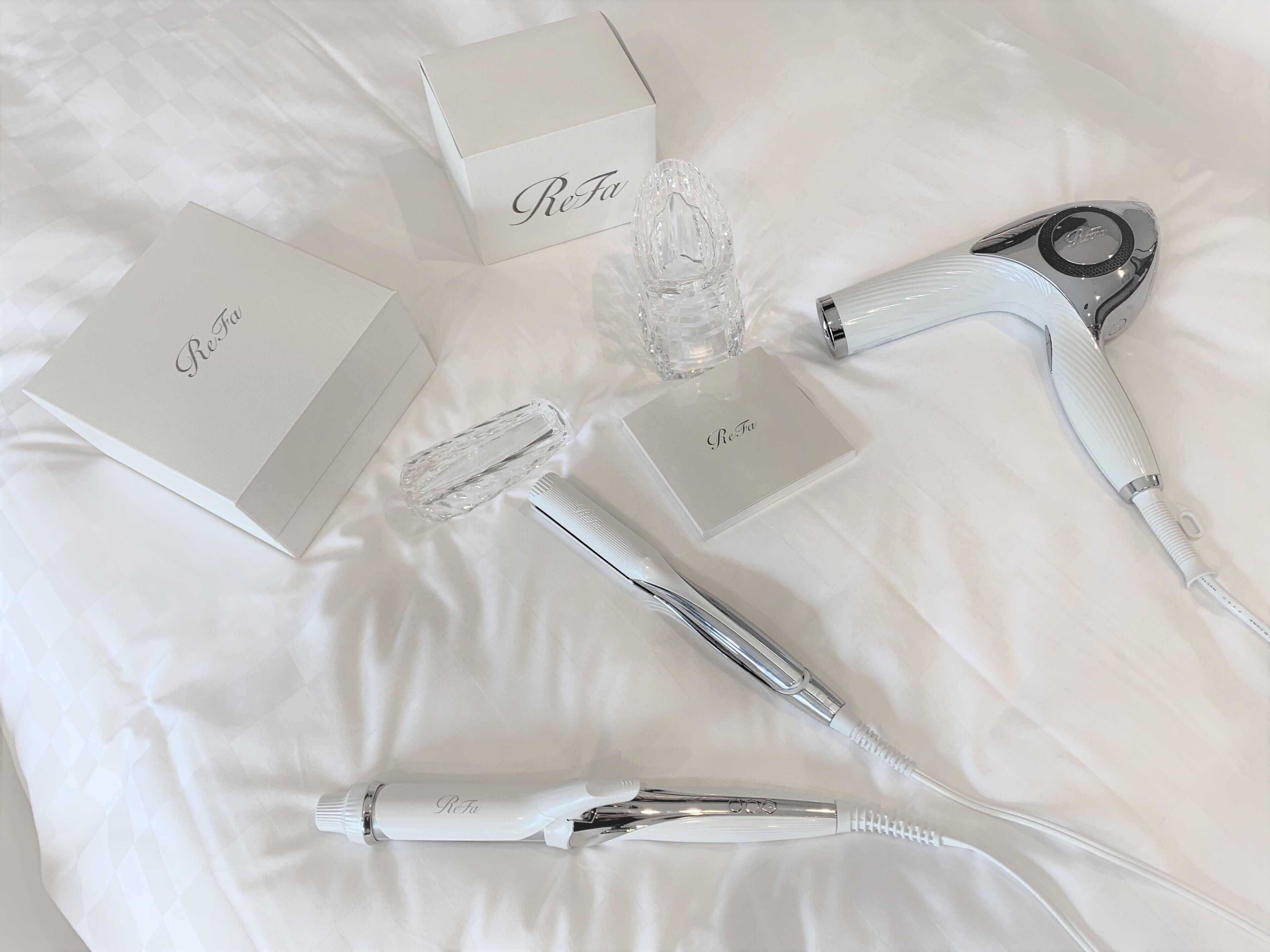 A neatly arranged set of personal care items on a white bedspread.