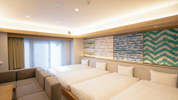 A hotel room with a sofa bed, a desk, and two single beds.