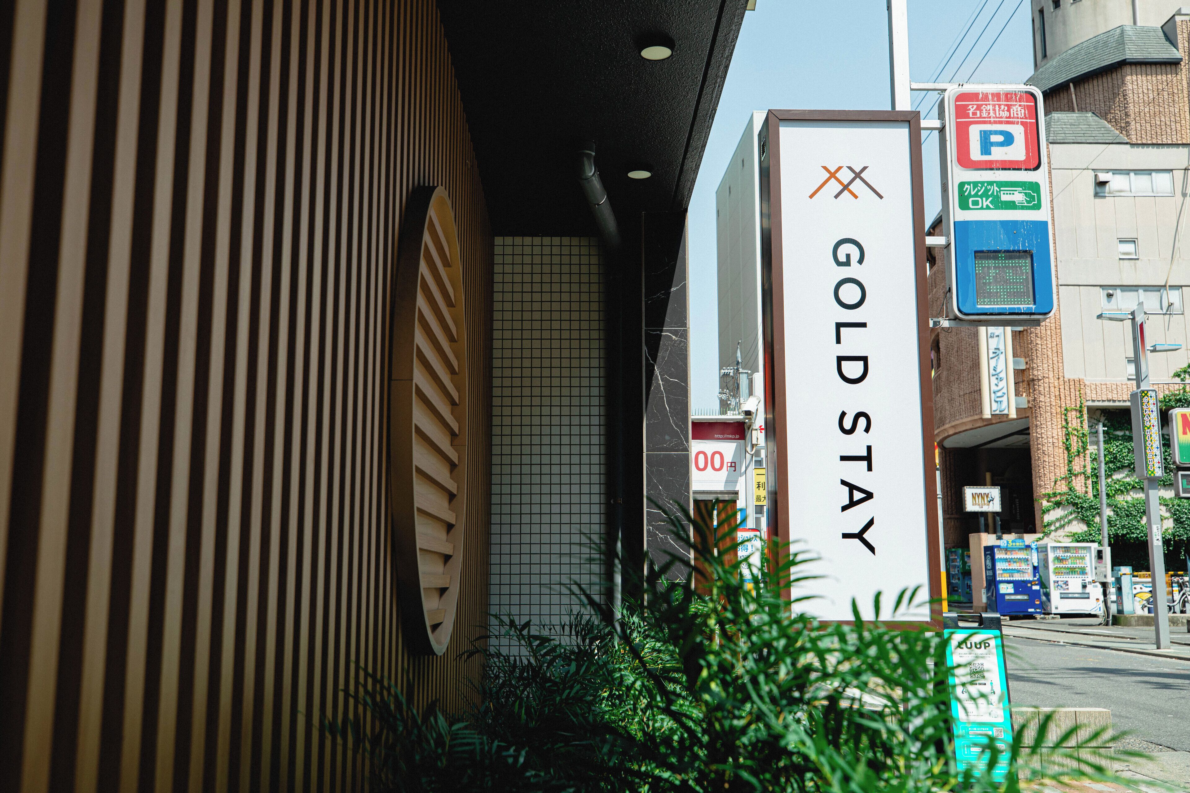 En hotellskylt med texten ”GOLD STAY” och en parkeringsskylt med en ”P”-symbol.