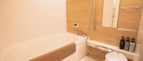 A modern bathroom with a bathtub, a shower, a toilet, and a vanity with toiletries.