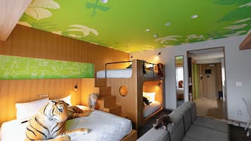 Une pièce avec un lit, un canapé, un chat et un tigre en peluche.