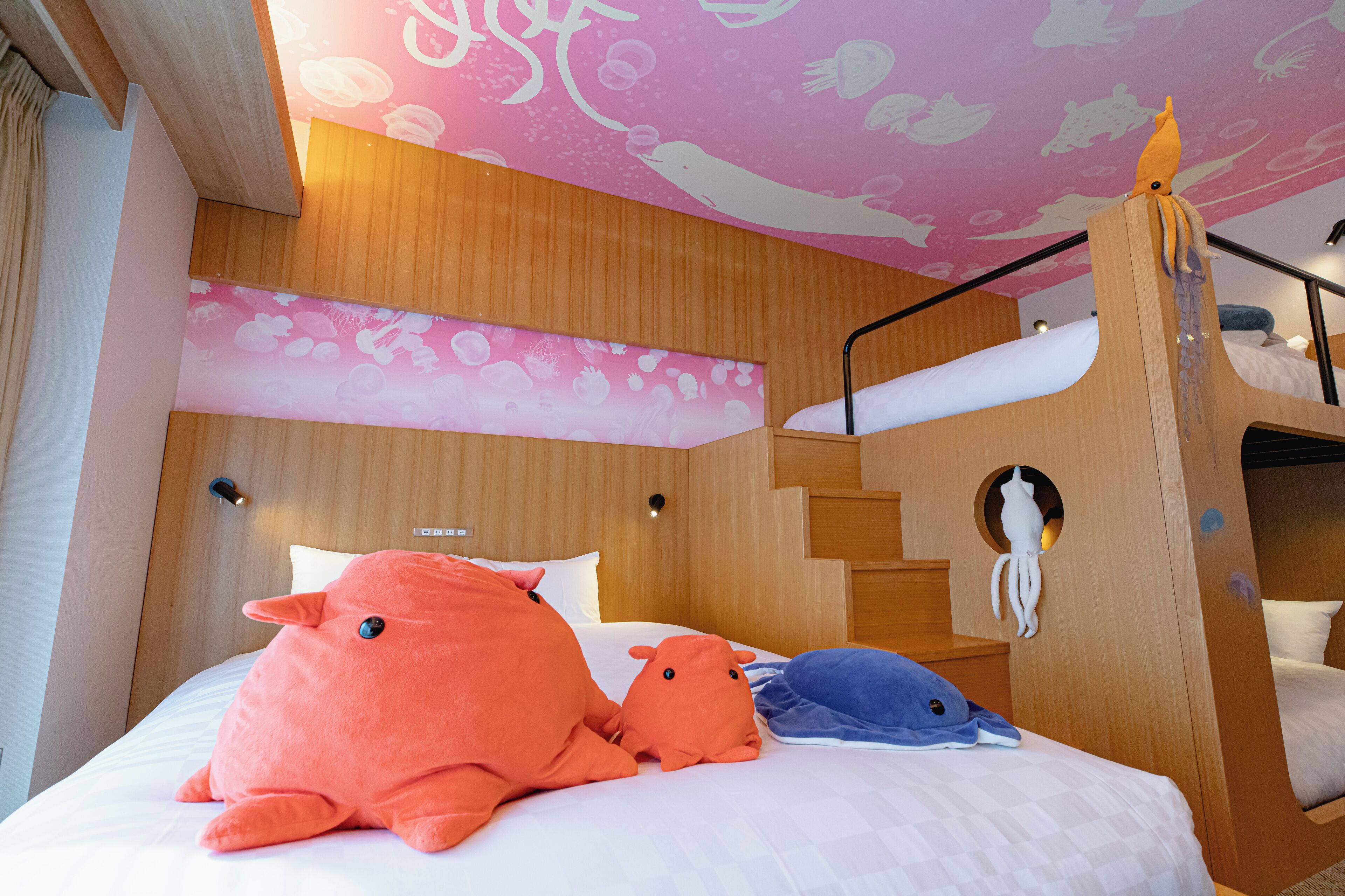 A bunk bed room with a pink ceiling, a wooden headboard, and a small octopus decoration.