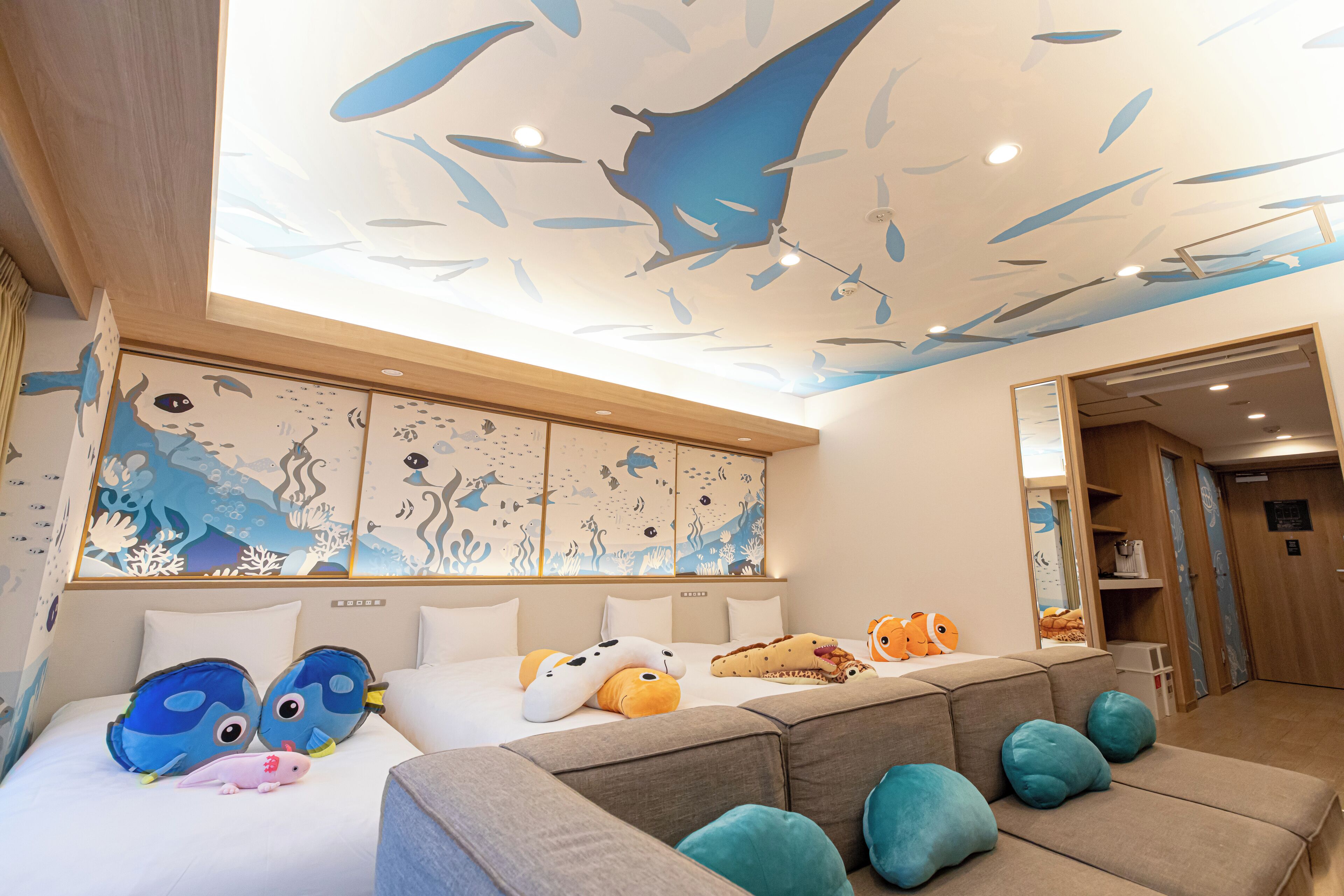 A hotel room with a bed, a sofa, and a ceiling mural of fish.