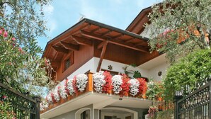 En traditionell chalet med en träbeklädd balkong som är prydd med blommor, stenväggar och en steninramad entré.