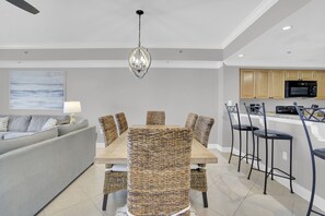 A modern kitchen with wooden cabinets, a microwave, and a dining area with a table and wicker chairs.