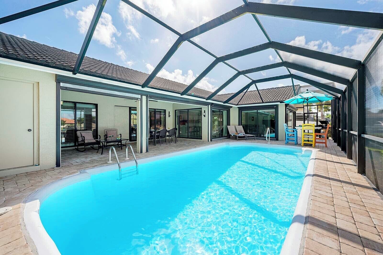 Ein überdachter Swimmingpool mit klarem, blauem Wasser, umgeben von Liegestühlen und einer Sonnenterrasse.