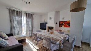 A modern living room with a dining table, sofa, and TV.