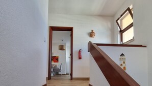 A staircase with wooden steps and a wooden handrail, leading to a room with a dining table and chairs.