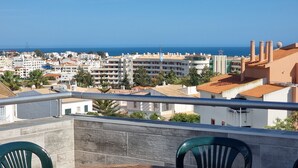 A balcony with a view of a coastal cityscape, including buildings and the sea.