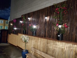 A bamboo wall with potted plants and a bench. - The Rumi Hostel (Los Angeles)