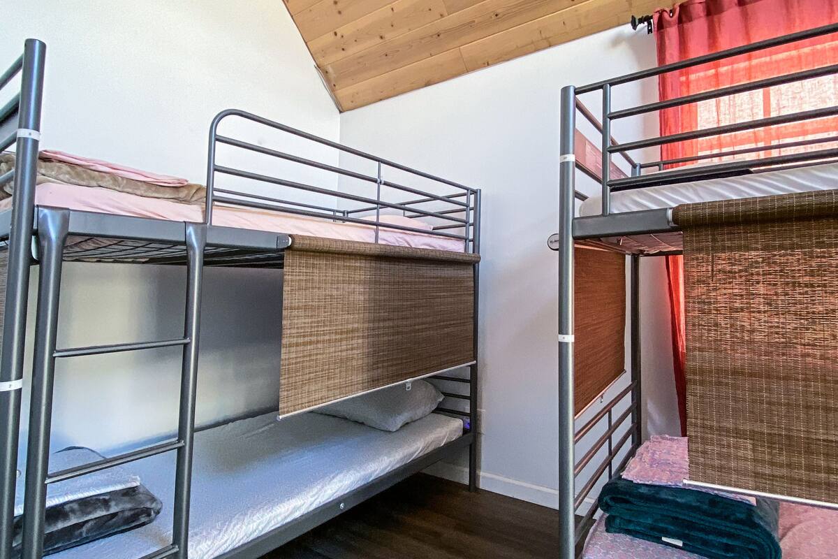 A bunk bed room with wooden ceiling and a red curtain.