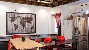 A conference room with a wooden table, red chairs, a world map on the wall, and a refrigerator.