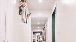 A hallway with a striped rug, a green door, and a mirror on the wall.
