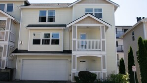 A two-story residential building with a white exterior, a front garage, and a balcony on the upper floor. - Lynnwood Airport-Retreat (Lynnwood)