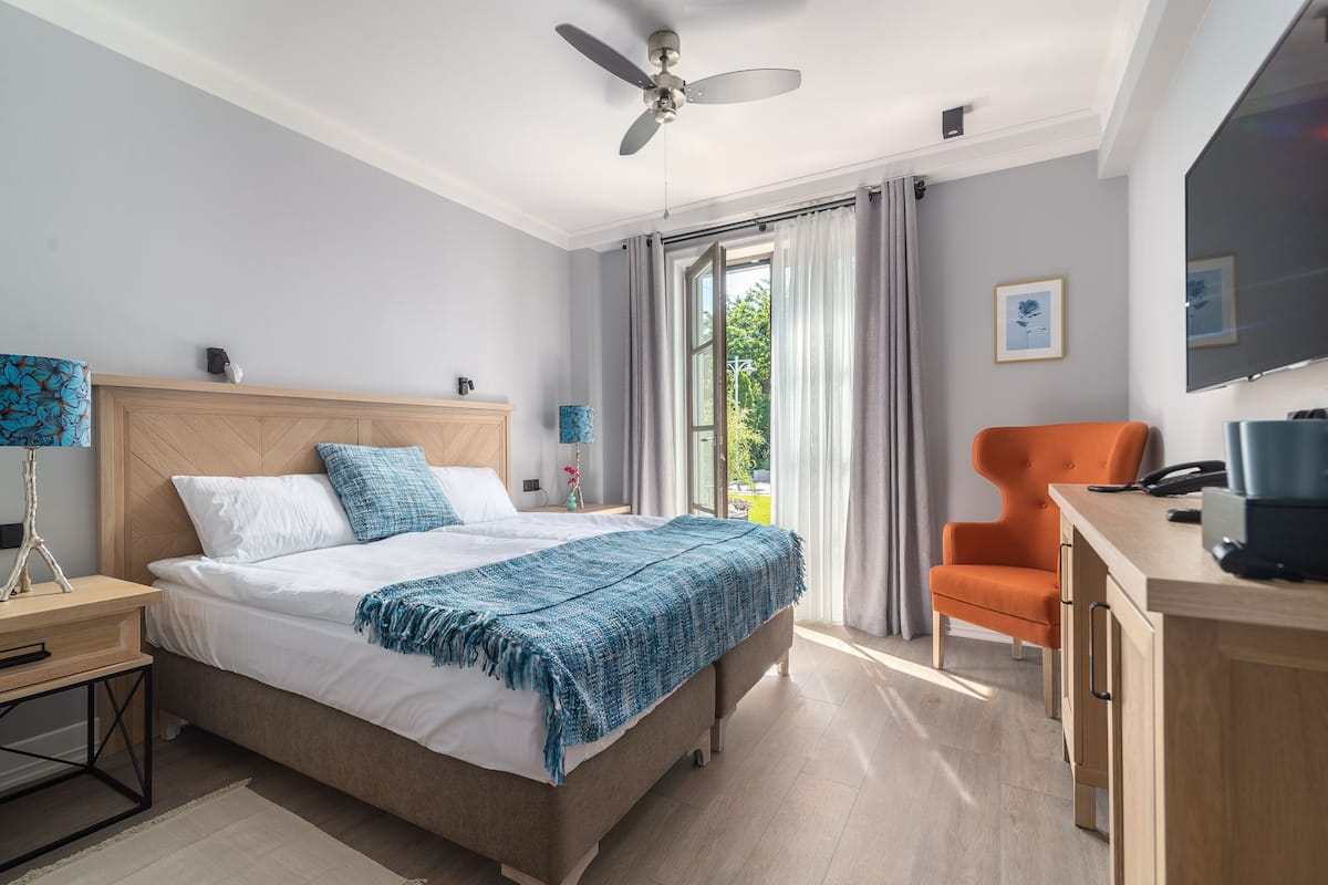 Une chambre moderne avec un lit, un bureau, une chaise orange et un ventilateur de plafond.