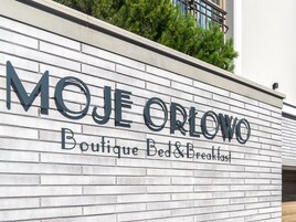 Señal de 'MOJE ORLOWO Boutique Bed & Breakfast' en una pared de ladrillo.
