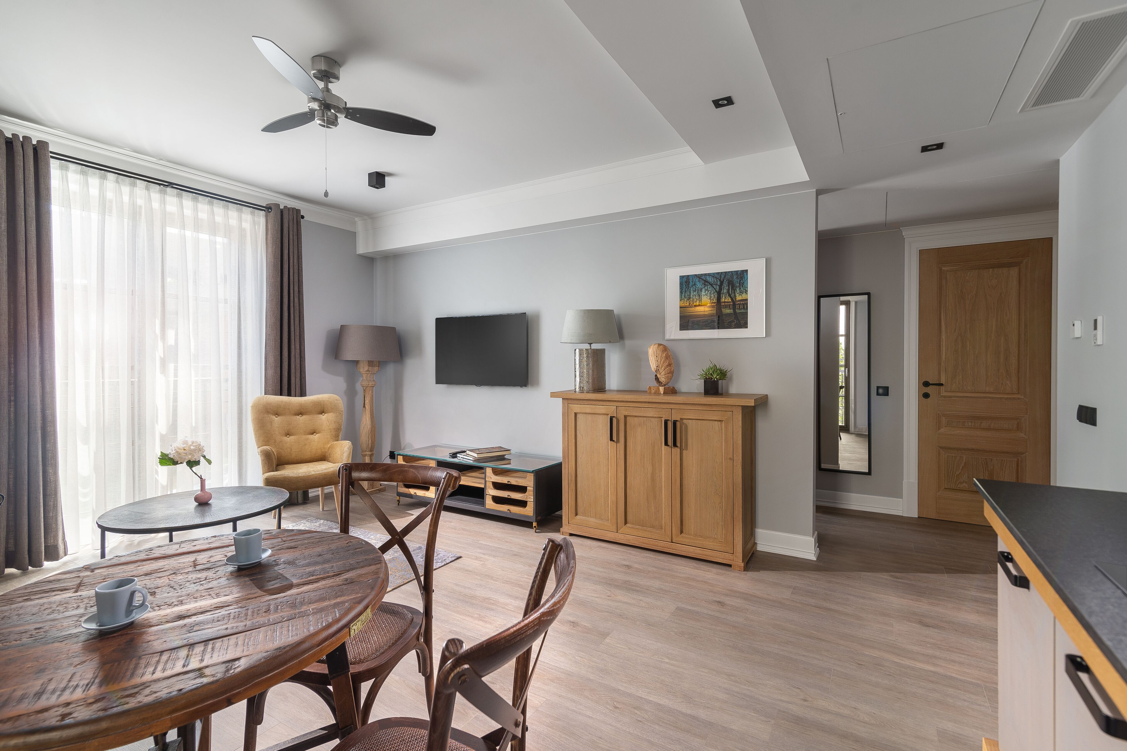 A modern living room with a dining table, chairs, a sofa, a TV, and a wooden cabinet.