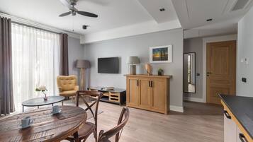 A modern living room with a dining table, chairs, a sofa, a TV, and a wooden cabinet.