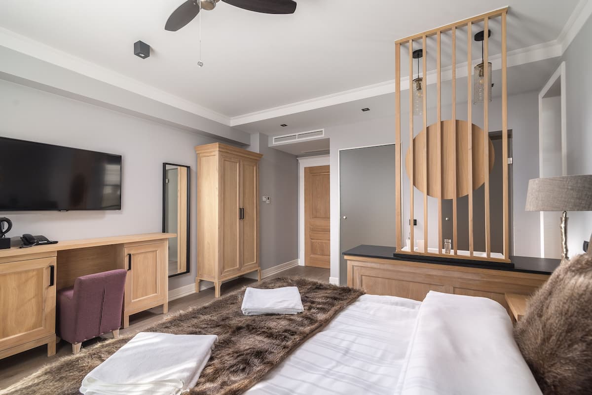 Une chambre d’hôtel moderne équipée d’un lit, d’un bureau, d’une armoire et d’un téléviseur.