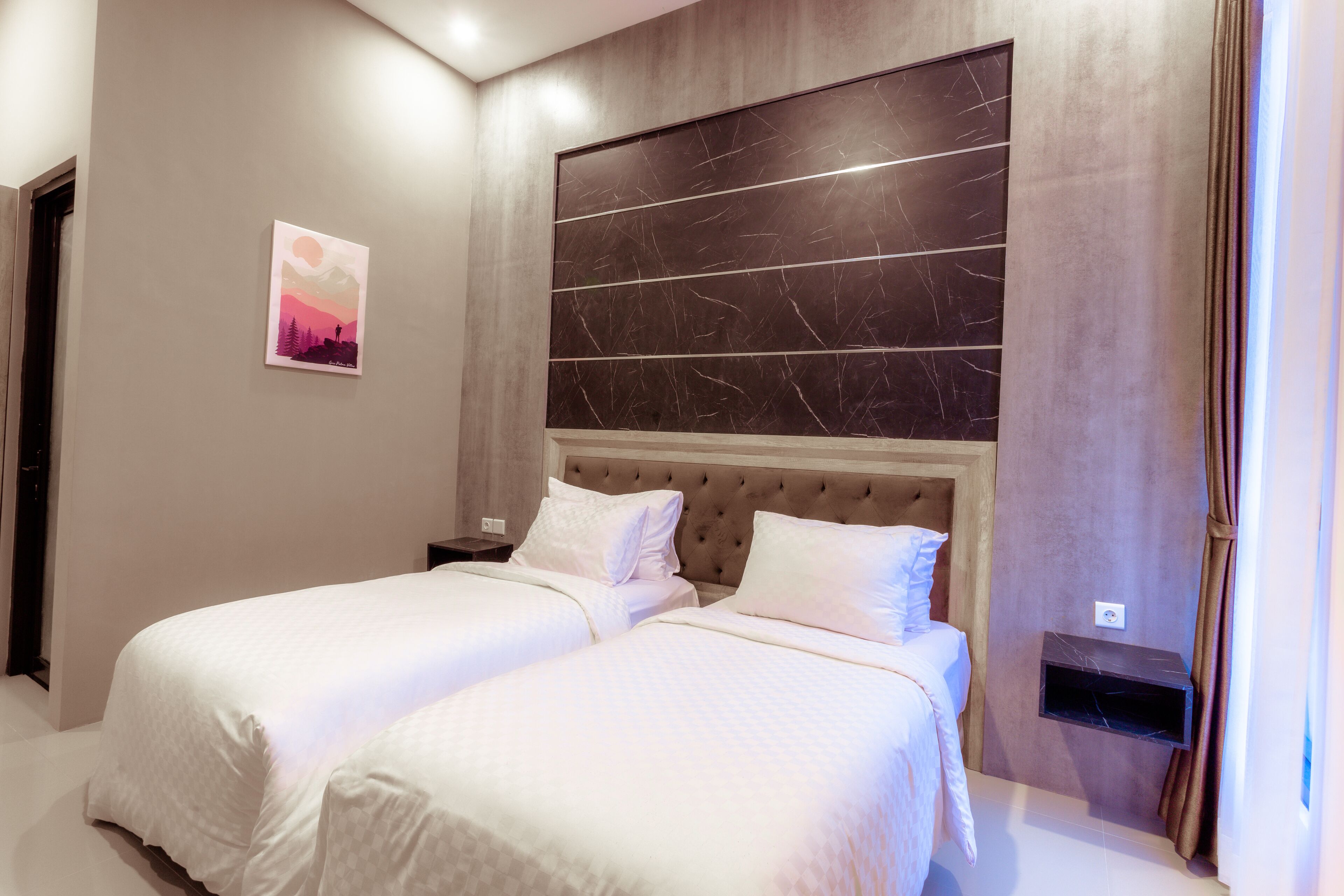 A modern hotel room with two beds, a marble headboard, and a small nightstand.