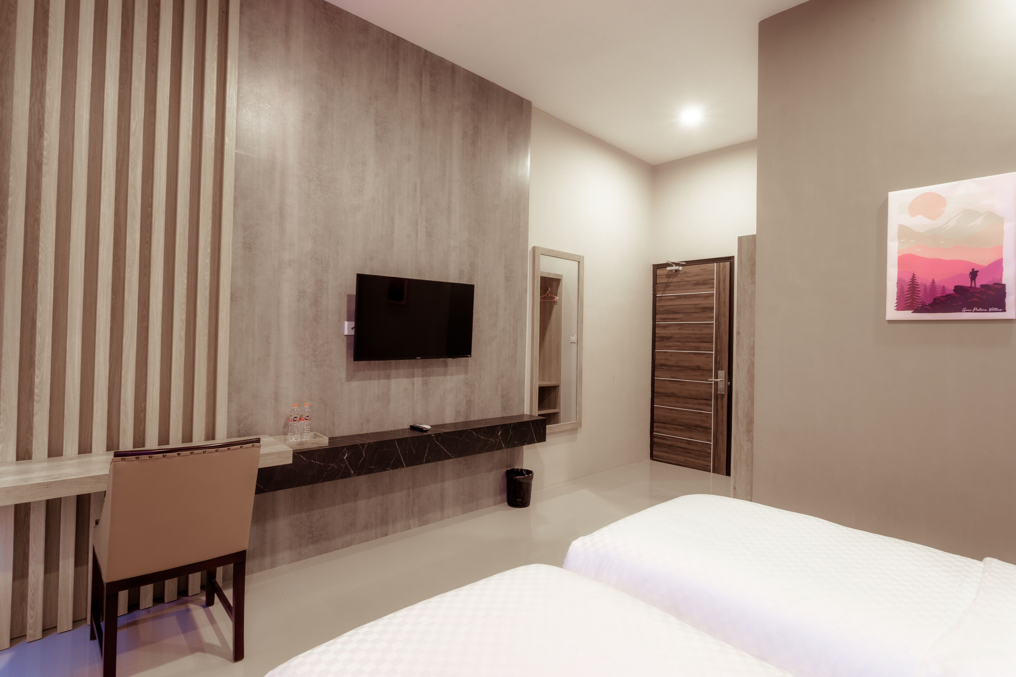 Habitación de hotel moderna con pared de listones de madera, televisor de pantalla plana, escritorio con silla, cama y un cuadro en la pared.