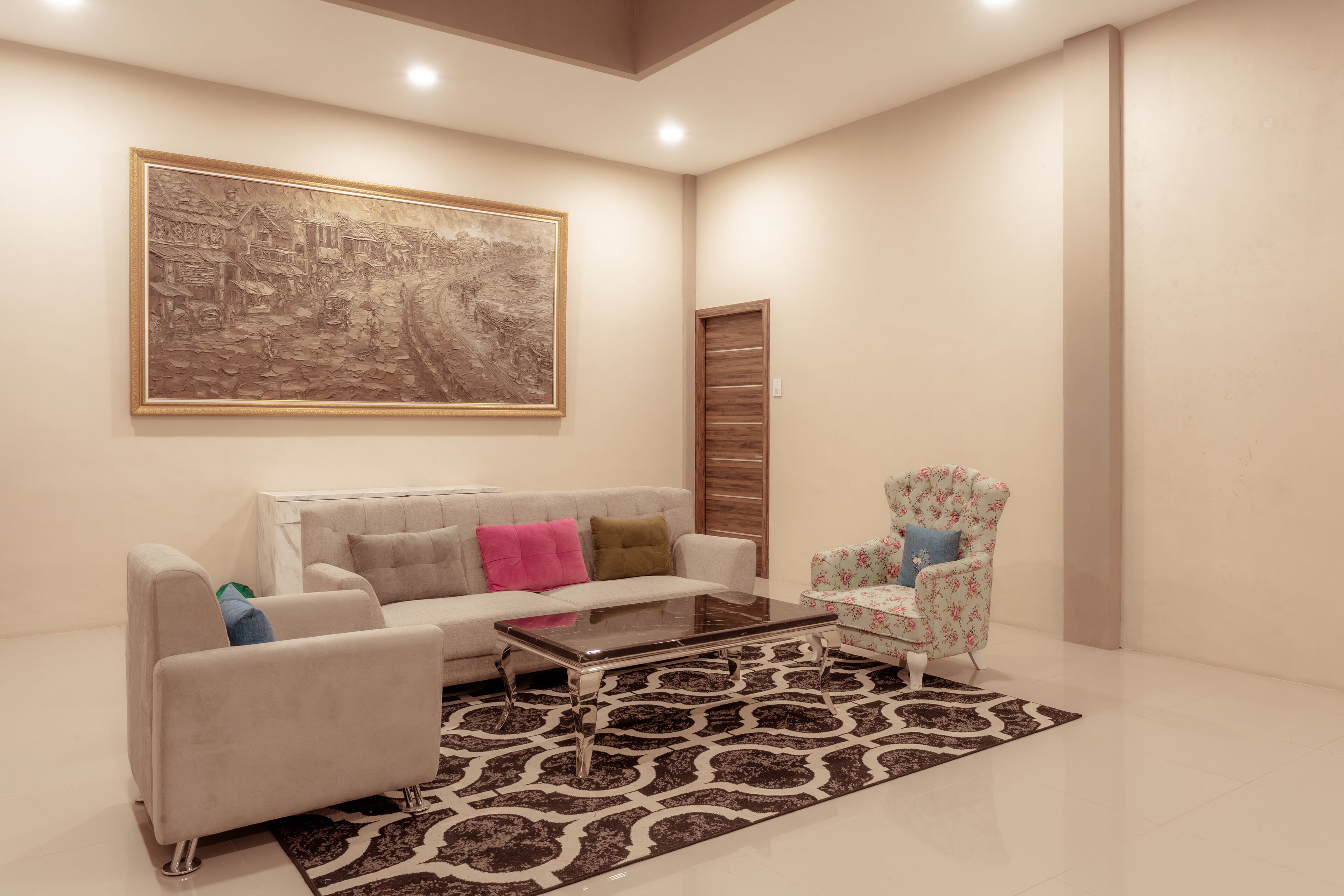 A modern living room with a sofa, armchairs, a coffee table, and a large framed artwork on the wall.