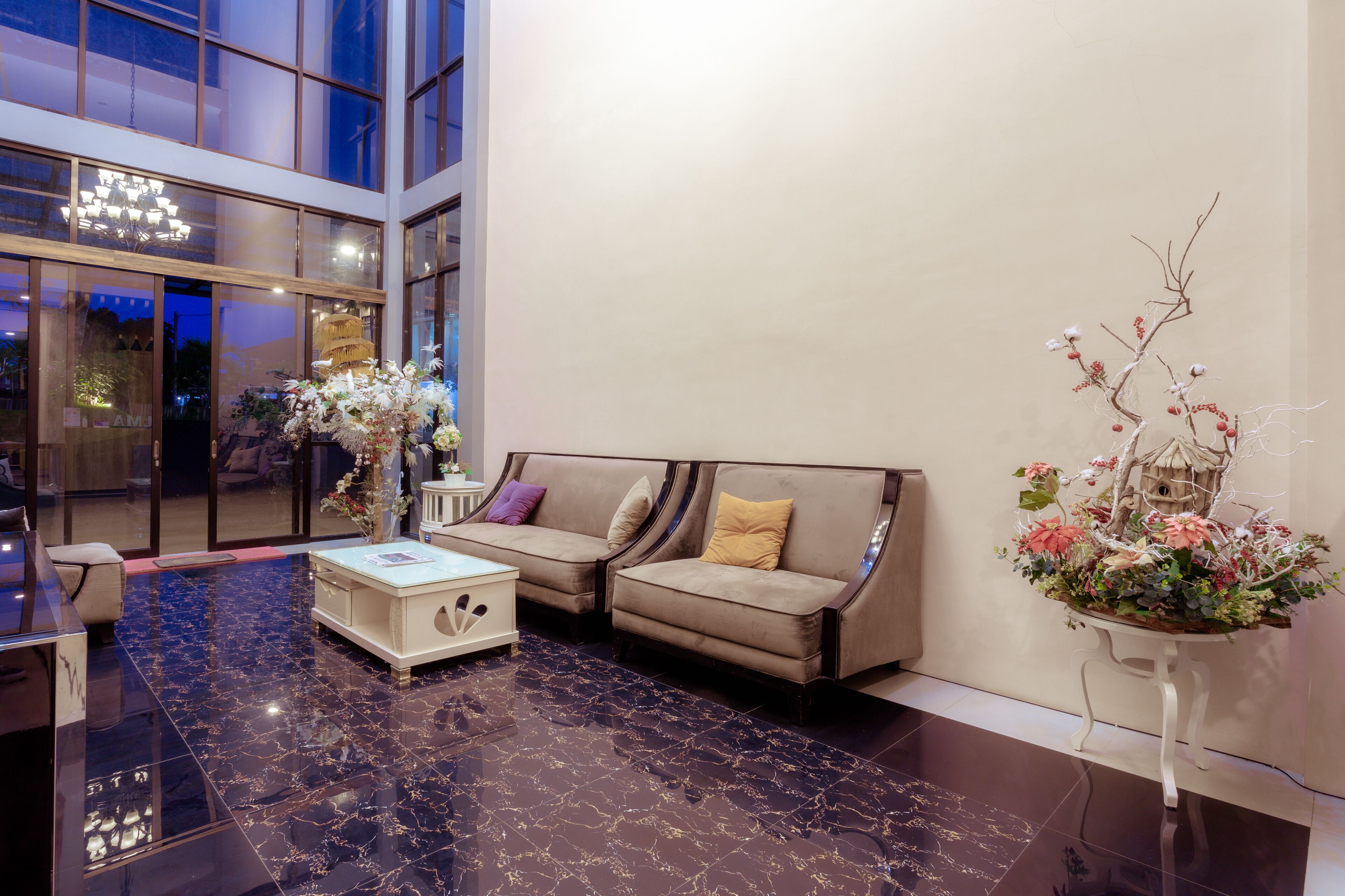 A modern lobby with a marble floor, a sofa with cushions, a coffee table, and a decorative plant.