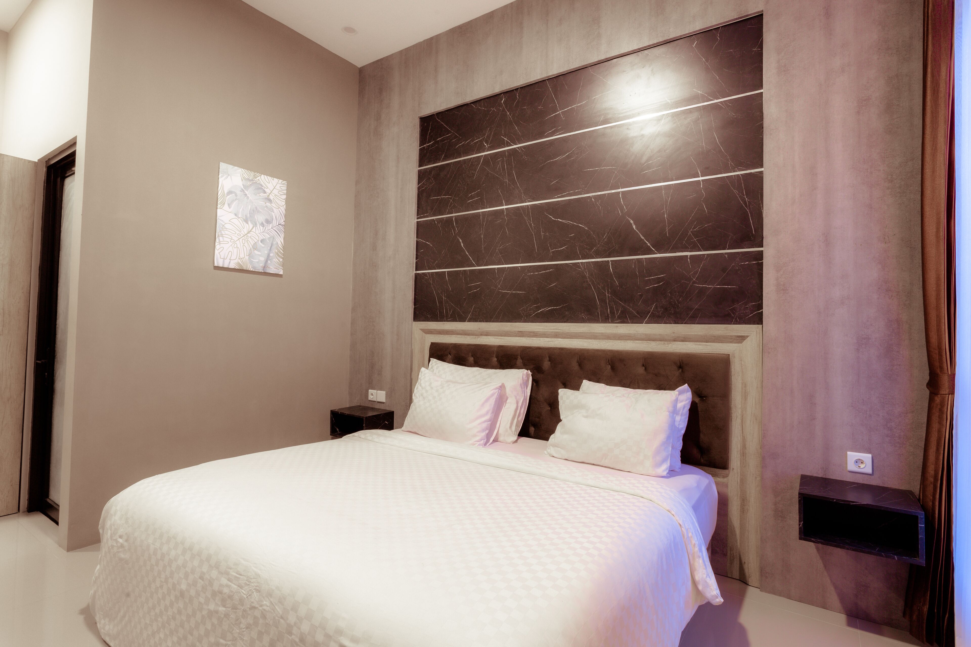 Une chambre moderne avec un grand lit, une tête de lit à motifs évoquant le marbre, une petite table de chevet et une étagère fixée au mur.