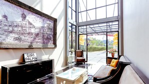 Un intérieur moderne avec une table basse en marbre, un canapé et un fauteuil. Un grand tableau orne le mur, et une enseigne indique « GIRI PALMA ».