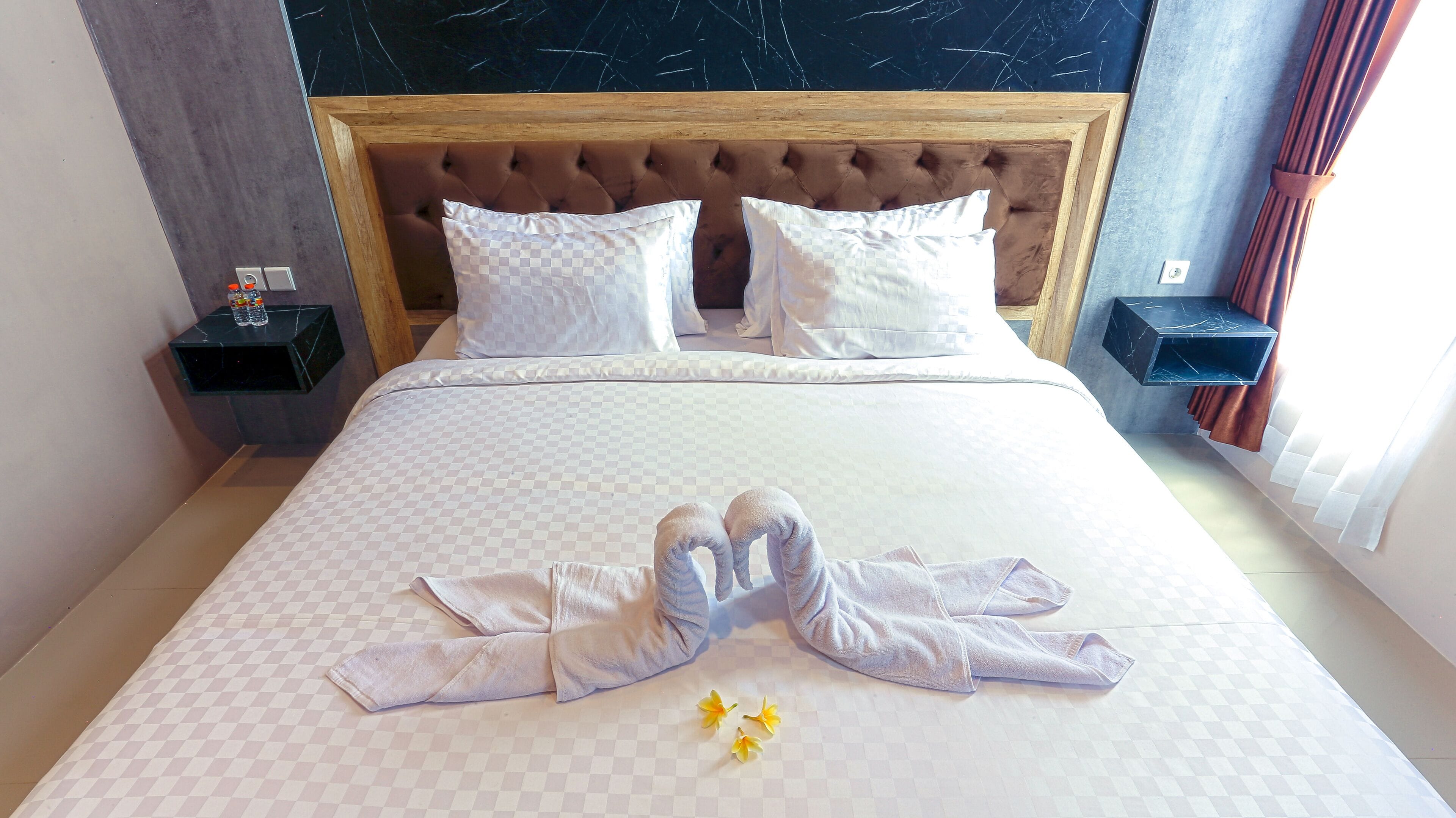 A neatly made bed with a checkered bedspread, two pillows, and a pair of towels arranged on the bed.