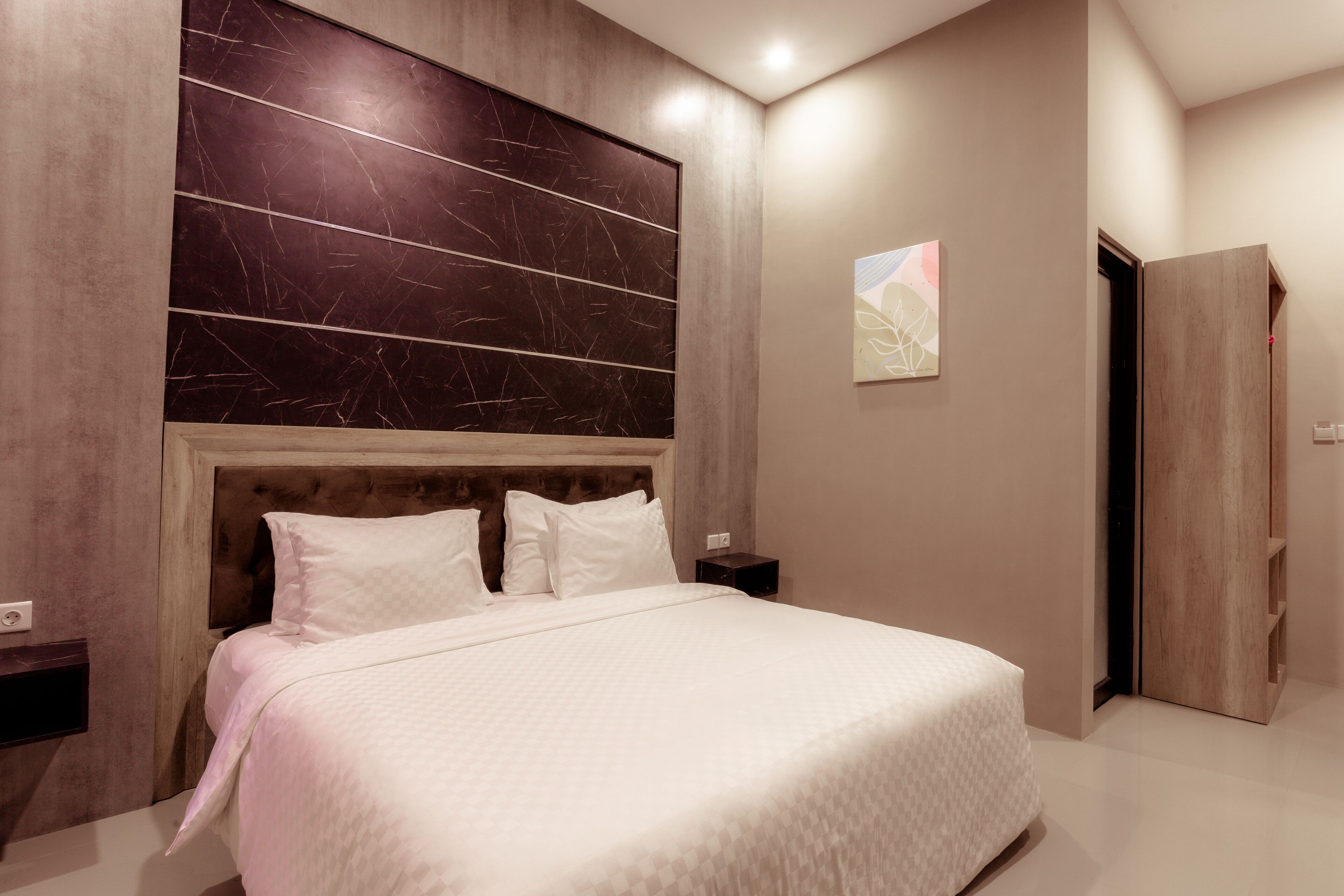 A modern bedroom with a large bed, wooden headboard, and a nightstand.