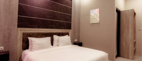 A modern bedroom with a large bed, wooden headboard, and a nightstand.