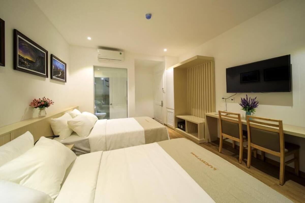 Een hotelkamer met twee bedden, een bureau, een stoel, een televisie en een raam.