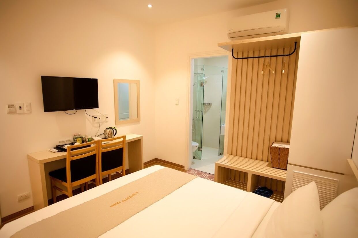 Une chambre d’hôtel comprenant un lit, un bureau avec des chaises, une télévision, un espace douche et une armoire.