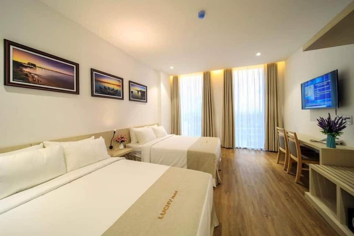 Een hotelkamer met twee bedden, een televisie, een bureau en een raam met gordijnen.