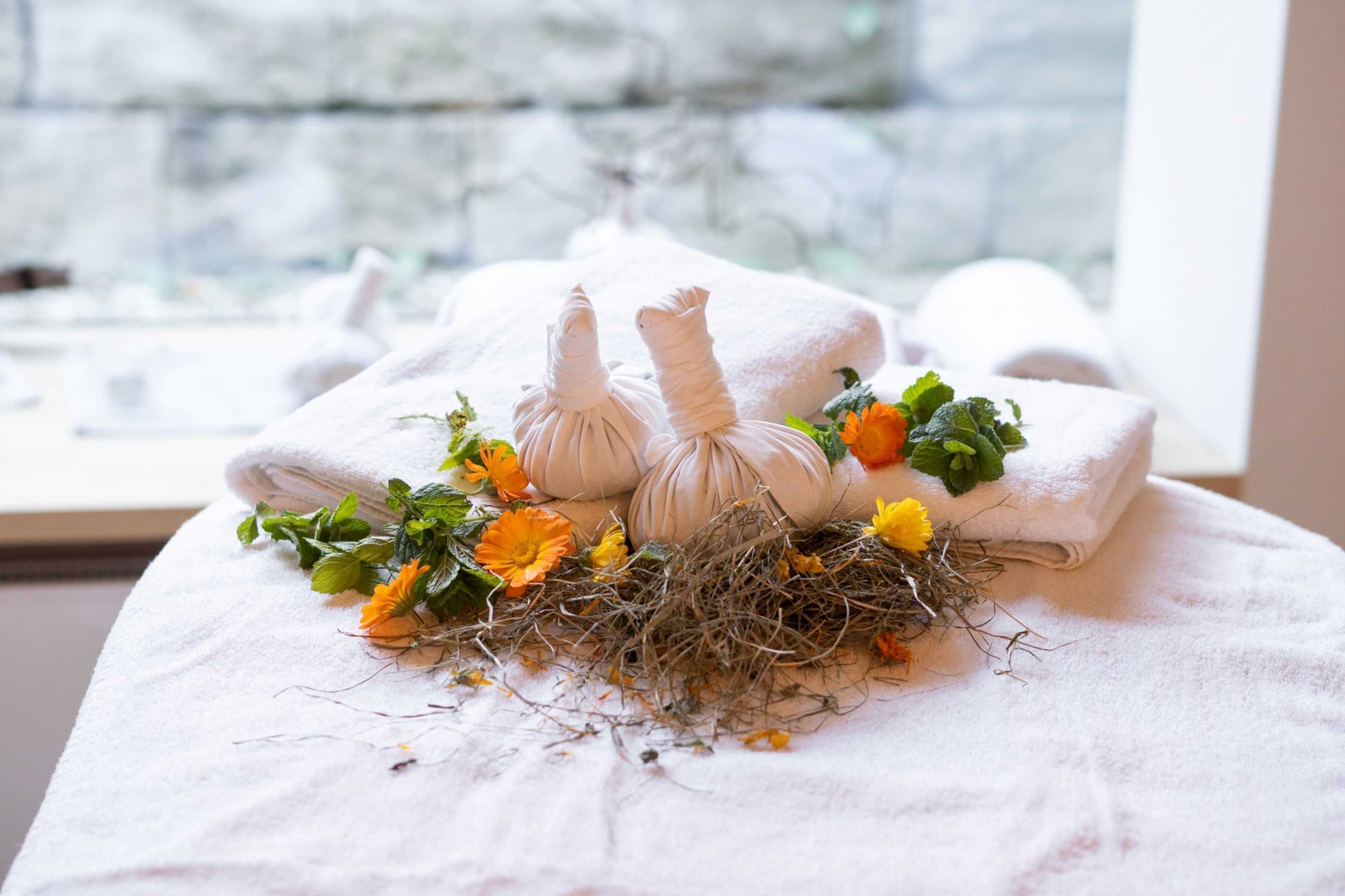 Ein ordentlich gefaltetes Handtuch mit einem Nest aus Zweigen und Blumen auf einem Bett.