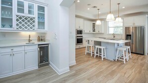 A modern kitchen with white cabinetry, stainless steel appliances, and a central island with bar stools.