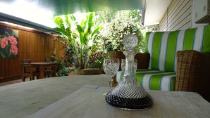 Comedor con una mesa dispuesta para dos personas, destacando un jarrón de vidrio decorativo y una silla de mimbre.