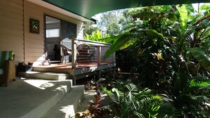 Una casa con porche, mobiliario exterior y un jardín con diversas plantas.