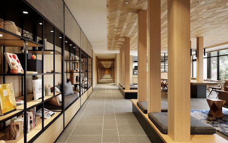 A modern interior with a long hallway, wooden columns, and seating areas.