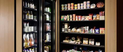 Ein gekühlter Verkaufsschrank mit Getränken und ein Regal, gefüllt mit Snacks und verpackten Waren.