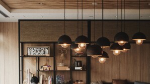 A modern interior with a wooden ceiling, black pendant lights, a bookshelf, and a seating area with a coffee table. - Fairfield by Marriott Kyoto Kyotamba (Kyotanba)