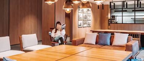 Un área de estar moderna con una gran mesa de madera, asientos cómodos e iluminación colgante.