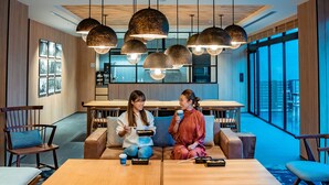 A modern dining area with a wooden table and chairs, pendant lighting, and a large window providing a view of the outdoors. - Fairfield by Marriott Kyoto Kyotamba (Kyotanba)