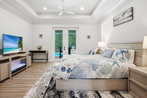 A bedroom with a bed, a TV, a desk, and a view of the outdoors.