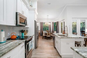 Enjoy cooking in this well-equipped kitchen with a central island, stainless steel appliances, and a dining area.