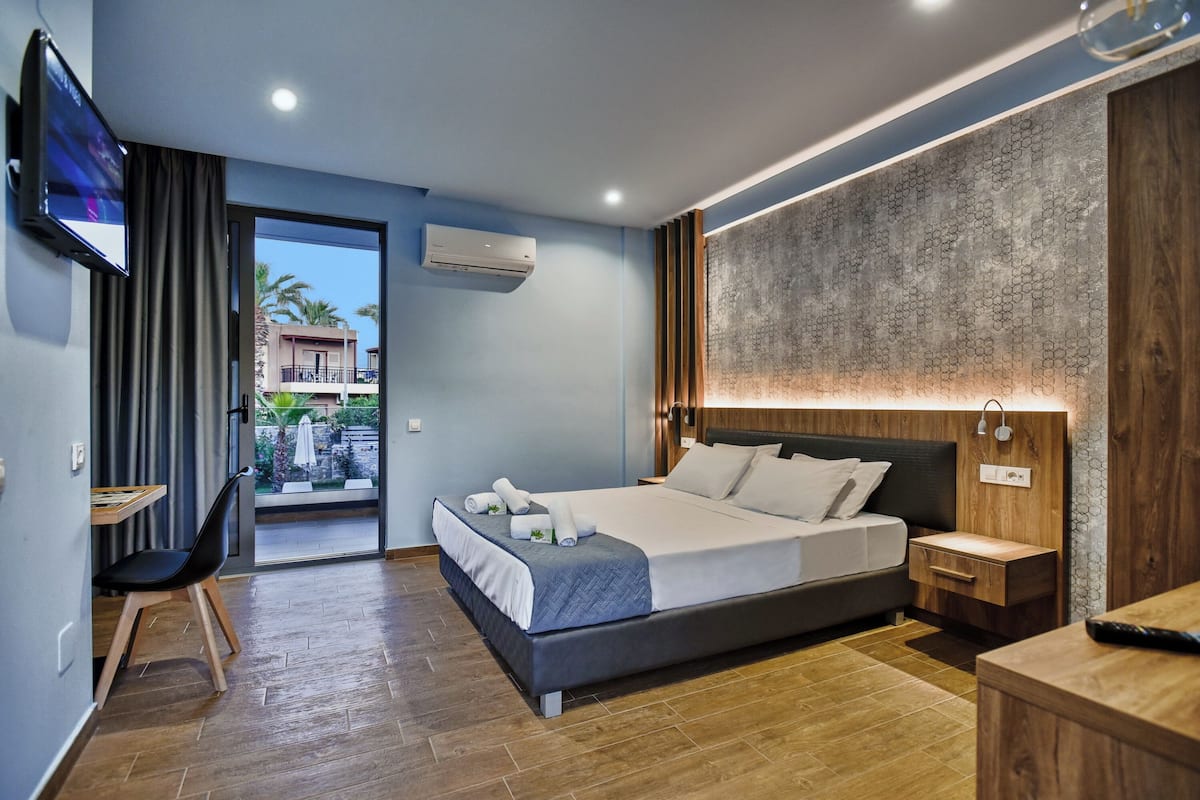 A modern hotel room with a large bed, a desk, and a TV.