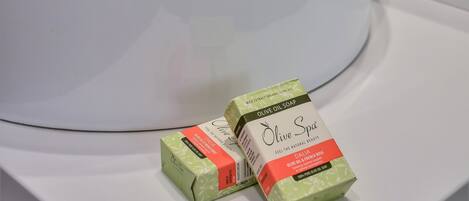 Un lavamanos blanco con dos cajas de jabón de aceite de oliva Olive Spa.
