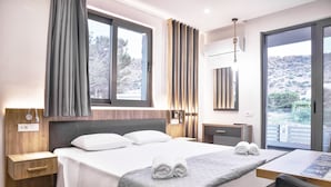 A hotel room with a bed, a desk, and a view of the outdoors. - Del Mar Apartments in Stalis (Hersonissos)